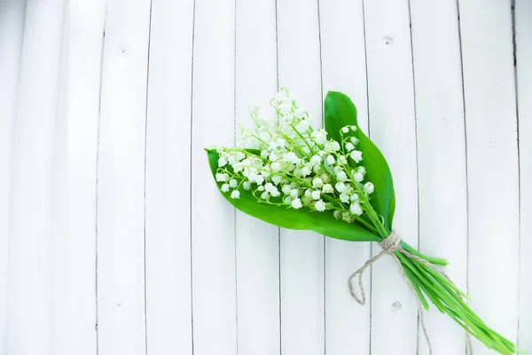 bouquet of lilies of the valley on a wooden white background with place for text