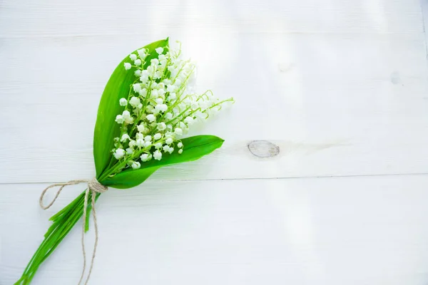 bouquet of lilies of the valley on a wooden white background with place for text