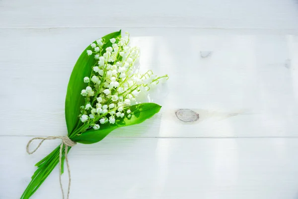 bouquet of lilies of the valley on a wooden white background with place for text