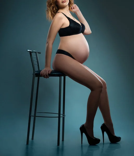 性感的怀孕女孩穿着黑色皮夹克内裤高跟鞋在工作室里 — 图库照片