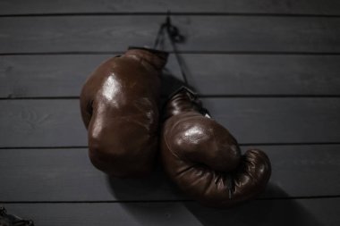Gri ahşap bir arka planda kahverengi, hakiki deriden yapılmış eski boks eldivenleri