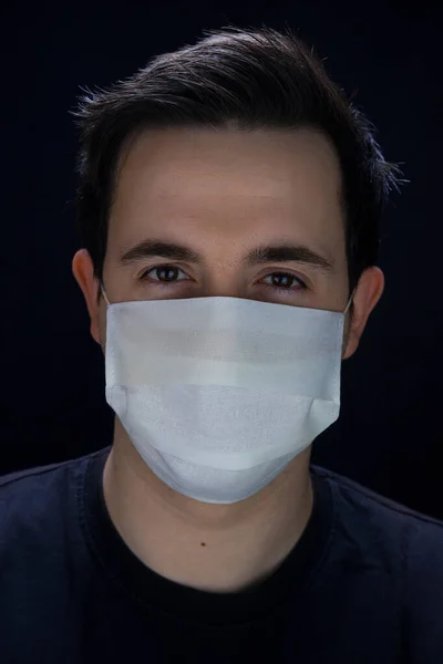 Man in a white medical mask for protection Covid-19in black background - Studio portrait