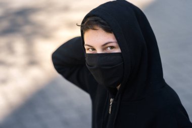 Siyah tıbbi maskeli bir genç sokakta