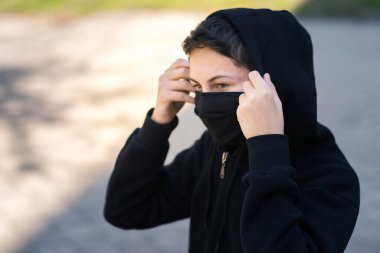Siyah tıbbi maskeli bir genç sokakta