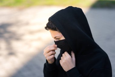 Siyah tıbbi maskeli bir genç sokakta