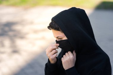 Siyah tıbbi maskeli bir genç sokakta