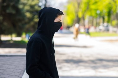 Siyah tıbbi maskeli bir genç sokakta