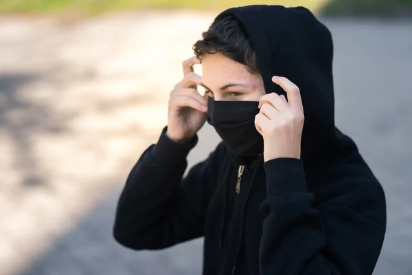 Siyah tıbbi maskeli bir genç sokakta