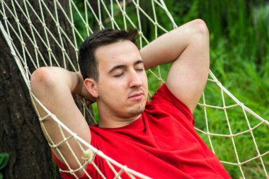 Genç, beyaz bir adam bir hafta sonu sabahında hamakta sallanıyor. Gülümsüyor.