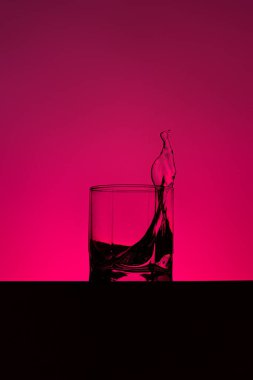 Su cama dökülüyor. Su parlak arka planda cama sıçrıyor. Şarap bardağına dökülen şeffaf sıvı. Yiyecek, nesne.