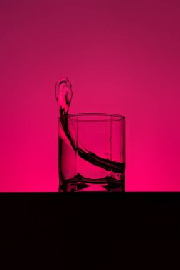 Su cama dökülüyor. Su parlak arka planda cama sıçrıyor. Şarap bardağına dökülen şeffaf sıvı. Yiyecek, nesne.