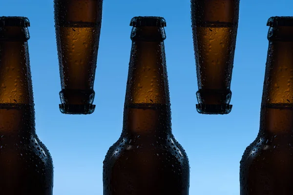 Fem Bruna Ölflaskor Med Droppar Dryck Utan Etikett Blå Bakgrund — Stockfoto