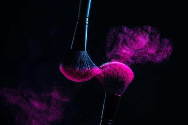 Cosmetic brushes in a bright palette of powder. Colorful explosion under makeup.