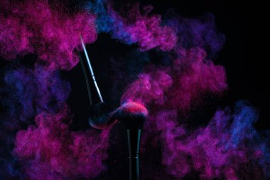 Durgun makyaj fırçası ve renkli toz bulutu. Kozmetik Fırçalar ve Patlama Renkli Tozlar. Pankart