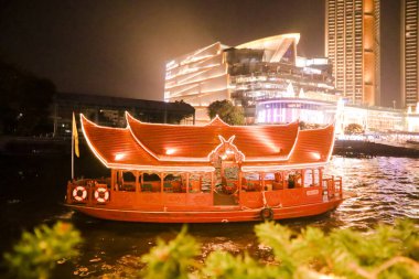 Bangkok 'un gece fotoğrafı ve nehirde yüzen bir seyahat teknesi. Büyük bir şehirde akşam hayatı
