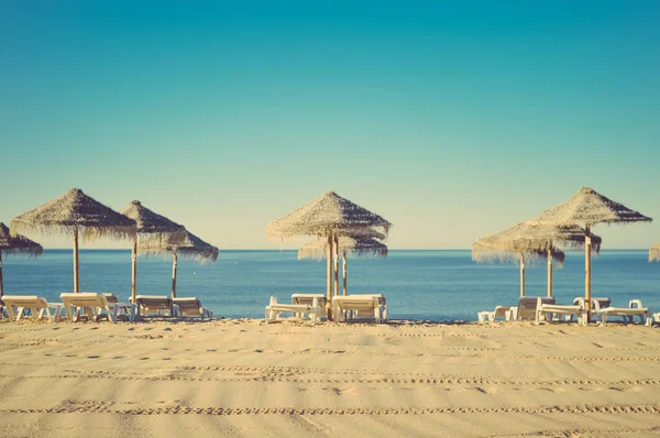 Hermosa vista de la playa con sombrillas de mimbre en el soleado cielo azul al aire libre fondo — Foto de Stock