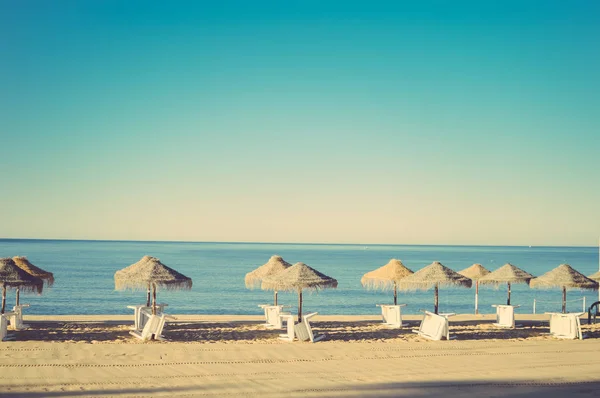 Wakacje i powołanie obrazu z beach lounge i parasol na tle sunny ocean morze na zewnątrz — Zdjęcie stockowe