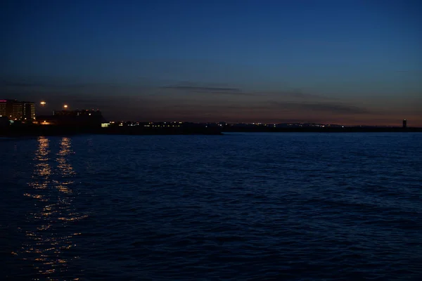 Luce offuscata della città bokeh con riflesso sullo sfondo dell'acqua — Foto Stock