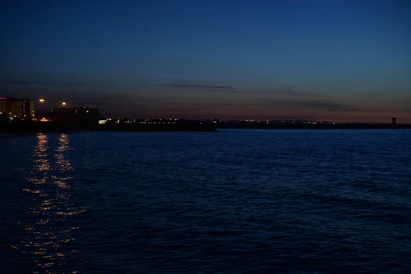 Luz borrosa de la ciudad bokeh con reflejo en el fondo de agua — Foto de Stock