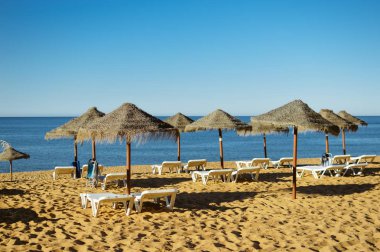 Mavi gökyüzü ve güzel tropikal plaj arka plan üzerinde saman şemsiye