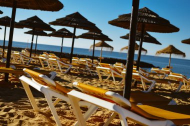 Mavi gökyüzü ve güzel tropikal plaj arka plan üzerinde saman şemsiye