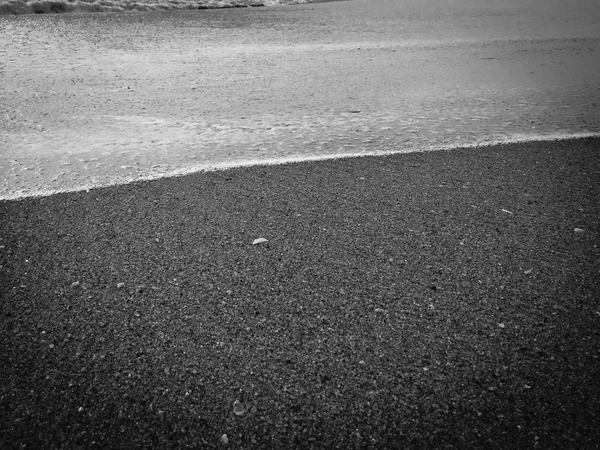 White ocean sea foam and black volcanic sandy surface beach backdrop top view background