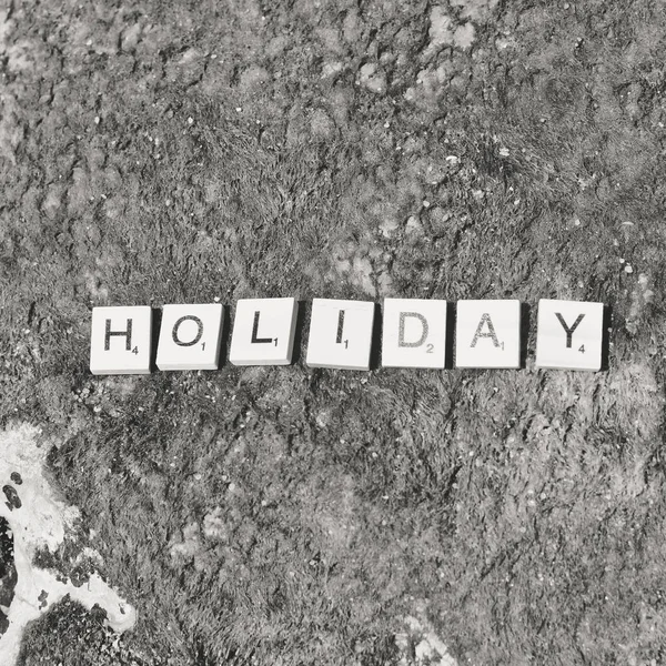 Top view on "Holiday" wooden sign pazzle abstract design on the beach background — Stock Photo, Image