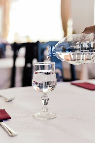 Air yang dituangkan ke dalam gelas anggur di atas meja latar belakang cahaya alami. Tutup. — Stok Foto
