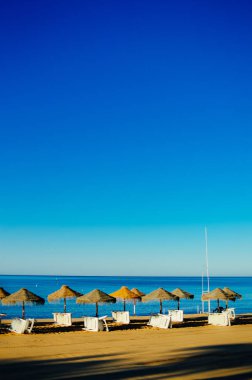 Güzel tropikal okyanus sahil şeridi, güneşli açık havada doğal arka plan üzerinde mavi gökyüzü ve plaj şemsiye sandalye