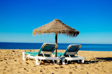 Güzel tropikal okyanus sahil şeridi, güneşli açık havada doğal arka plan üzerinde mavi gökyüzü ve plaj şemsiye sandalye