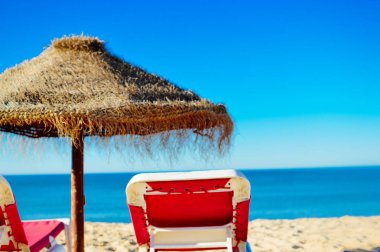 Güzel tropikal okyanus sahil şeridi, güneşli açık havada doğal arka plan üzerinde mavi gökyüzü ve plaj şemsiye sandalye