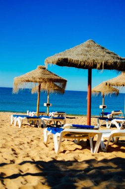 Güzel tropikal okyanus sahil şeridi, güneşli açık havada doğal arka plan üzerinde mavi gökyüzü ve plaj şemsiye sandalye