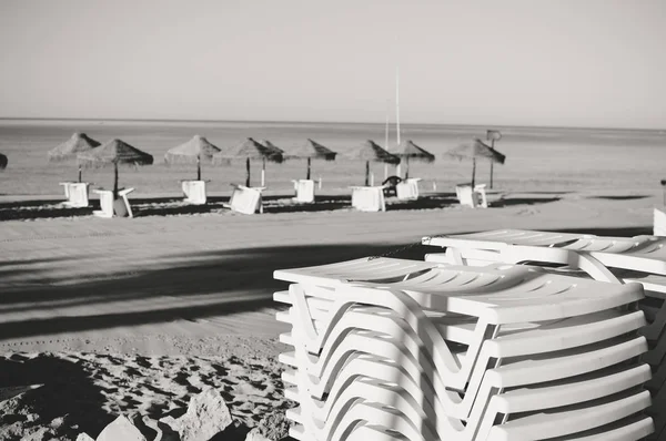 Des chaises longues de plage de vacances et une verrière de parasol sur l'océan en plein air. Photographie noir et blanc image — Photo