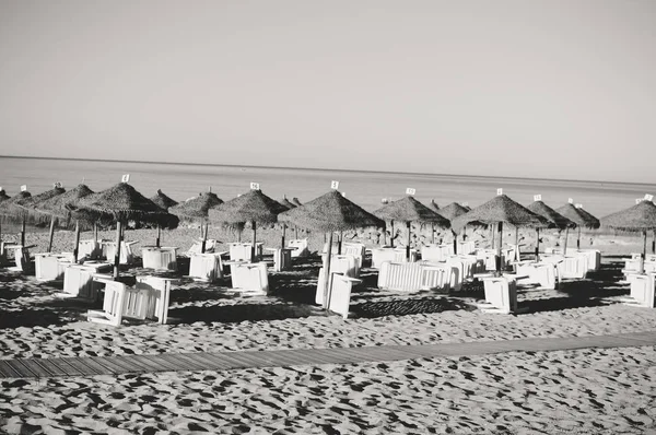Tatil plaj şezlong ve şemsiye gölgelik okyanus açık havada arka plan üzerinde. Siyah ve beyaz fotoğraf görüntü — Stok fotoğraf