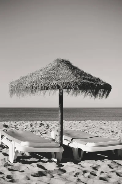 Parasole plażowe i kanapy na tle na zewnątrz niebo. Obraz czarno-biały — Zdjęcie stockowe