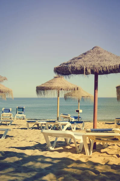 Niebieski niebo i plaży parasol krzesło na piękne tropikalne ocean wybrzeża, tło sceniczny słoneczny na zewnątrz — Zdjęcie stockowe