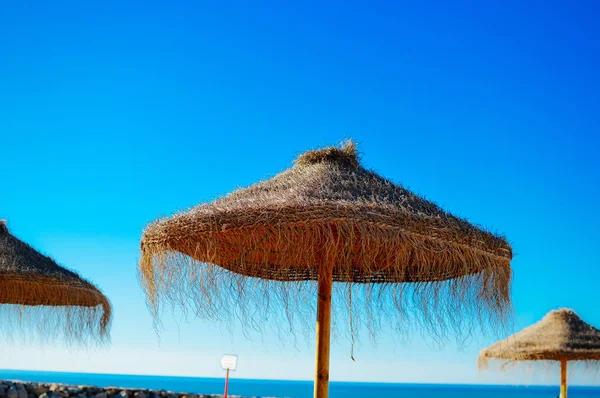 Parasols en banken op buitenshuis blauwe hemelachtergrond — Stockfoto