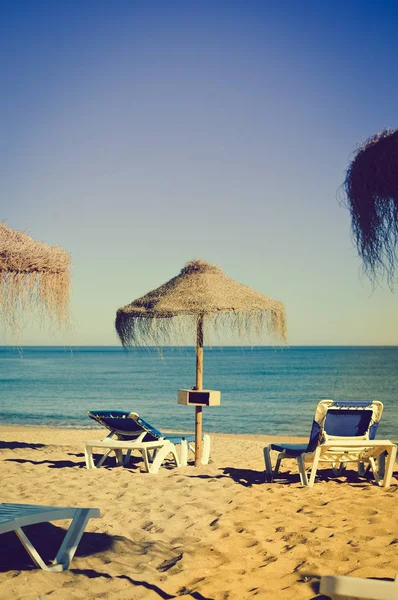 Parasole plażowe i kanapy na tle na zewnątrz niebieski niebo — Zdjęcie stockowe