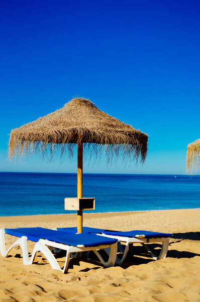 Beach umbrellas and couches on outdoors blue sky background