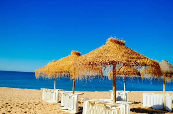 Chaise lounges de playa de vacaciones y toldo sombrilla en el fondo del océano al aire libre — Foto de Stock