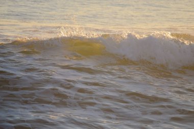 Güneşli su, okyanus dalgası, gün batımını bulanıklaştırdı.