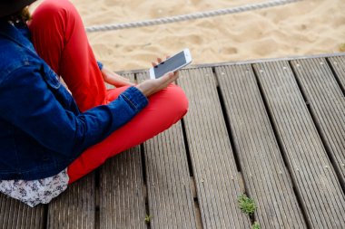 Closeup kumlu plaj arka plan üzerinde hareket eden smartphone kullanan kişi üzerinde. Çevrimiçi bağlantı, iletişim mesajlaşma, bankacılık için fotoğraf konsepti.