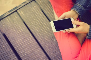 Closeup kumlu plaj arka plan üzerinde hareket eden smartphone kullanan kişi üzerinde. Çevrimiçi bağlantı, iletişim mesajlaşma, bankacılık için fotoğraf konsepti.