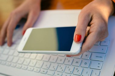 Bilgisayar ve cep telefonu kullanarak çalışan eller kadın. Sahte smartphone ekran ağ bağlantısı closeup görünümü