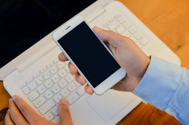 Adam bilgisayar ve cep telefonu kullanarak çalışan eller. Sahte smartphone ekran ağ bağlantısı tablo arka plan üzerinde görünümünü portre