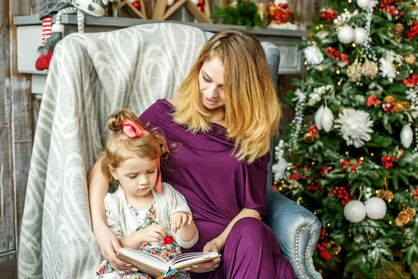 ママは、彼女の小さな娘に本を読みます。メリー クリスマスの概念 — ストック写真