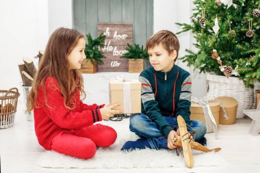 Küçük kardeş kardeşi için bir hediye sunuyor. Mutlu Noeller bir