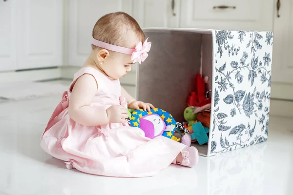 Hermoso bebé obtiene juguetes de la caja. Vestido rosa . — Foto de Stock
