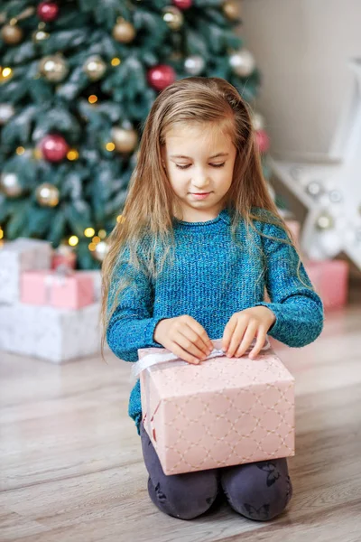 Mała dziewczynka otwiera prezent na Boże Narodzenie rano. Koncepcja nowego tak — Zdjęcie stockowe