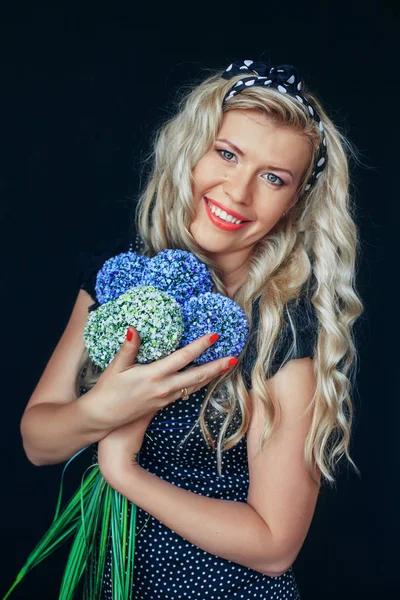 Doce menina loira com flores em um fundo preto. A arrogância — Fotografia de Stock